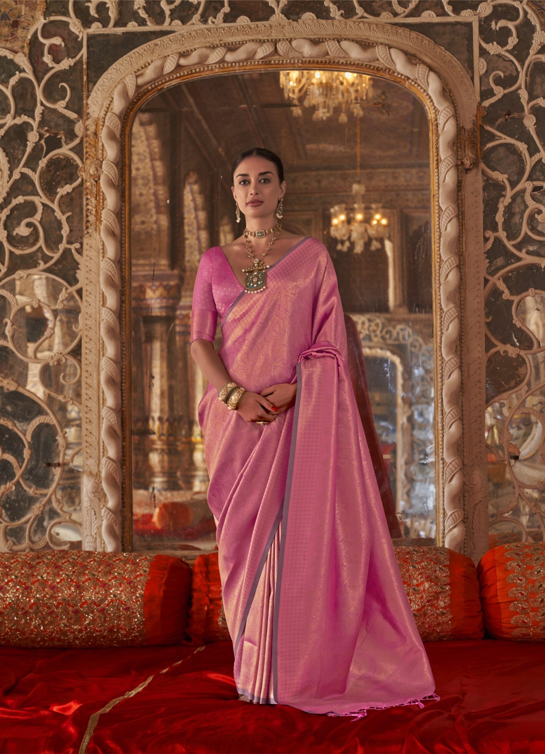 "Blush Palace Shimmer Silk Saree: A majestic orchid pink saree featuring an all-over gold zari woven brocade pattern and a rich metallic shimmer, modeled in a royal palace setting."