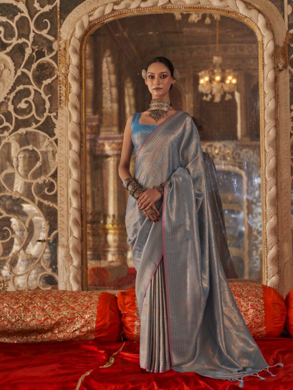 Model wearing a Mist Blue Zari Silk Saree with silver brocade work and antique silver jewelry in a royal palace setting.